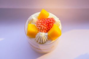 Top view of fruit mousse dessert with fresh mango and strawberry, on a bright background.