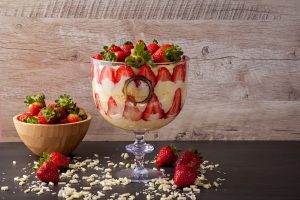 Luscious strawberry trifle with fresh berries and cream in a glass bowl for a delightful dessert.